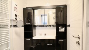 Ein Badezimmer mit einem weißen Waschbecken, schwarzen Schränken und einem Spiegel darüber.