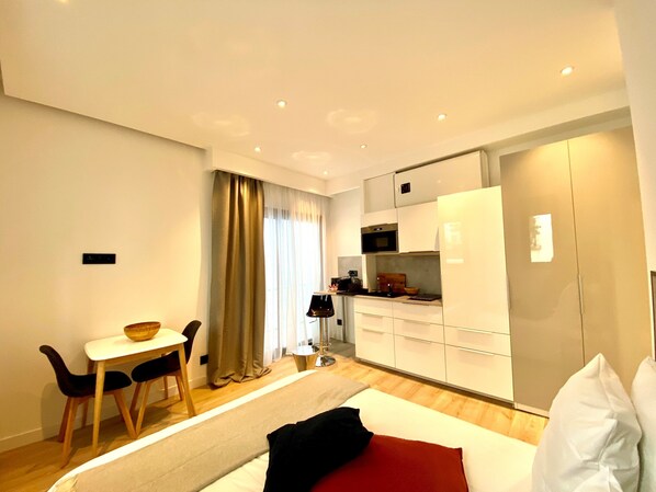 A modern hotel room with a bed, a dining area with a table and chairs, a kitchen area with a microwave, and a large wardrobe. - B8 Mini Studio 175Blo-Paris Convention (Paris)