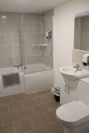 A bathroom with a glass-enclosed shower, a white sink, and a toilet. - Park Hotel & Apartments (Hull)