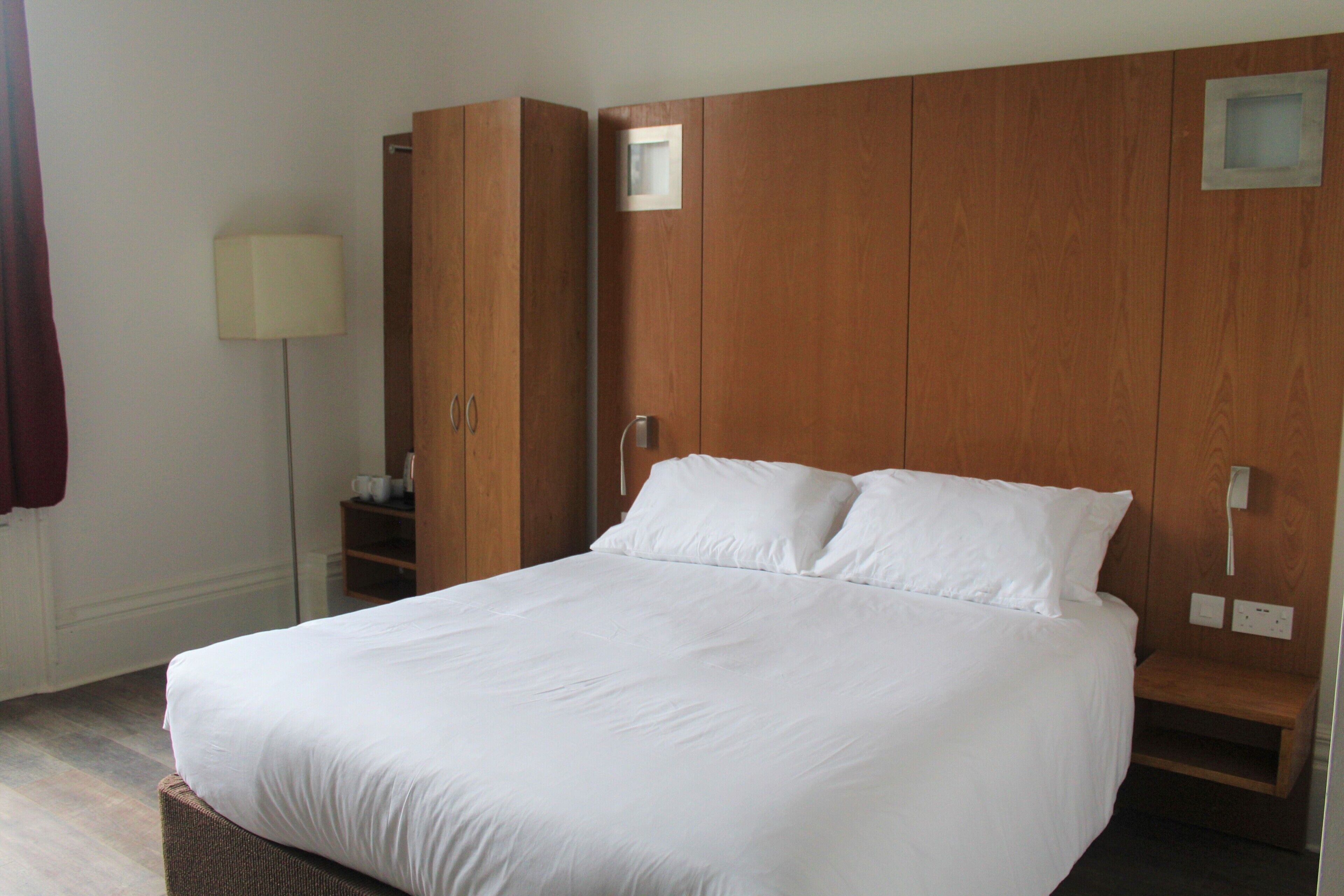 Un dormitorio con una cama grande, un armario de madera y una mesita de noche.