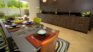 Een moderne keuken met een eetgedeelte, met een grote tafel gedekt voor een maaltijd, een keukeneiland en uitzicht op de omgeving.