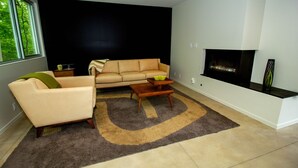 A modern living room with a beige sofa, a coffee table, and a fireplace.