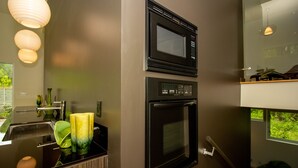 Een moderne keuken met een ingebouwde magnetron, oven en een raam met uitzicht op groen.