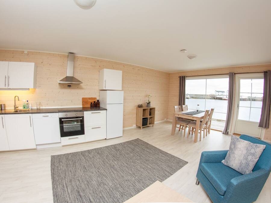 A modern kitchen with white cabinets, a built-in oven, and a dining area with a table and chairs.