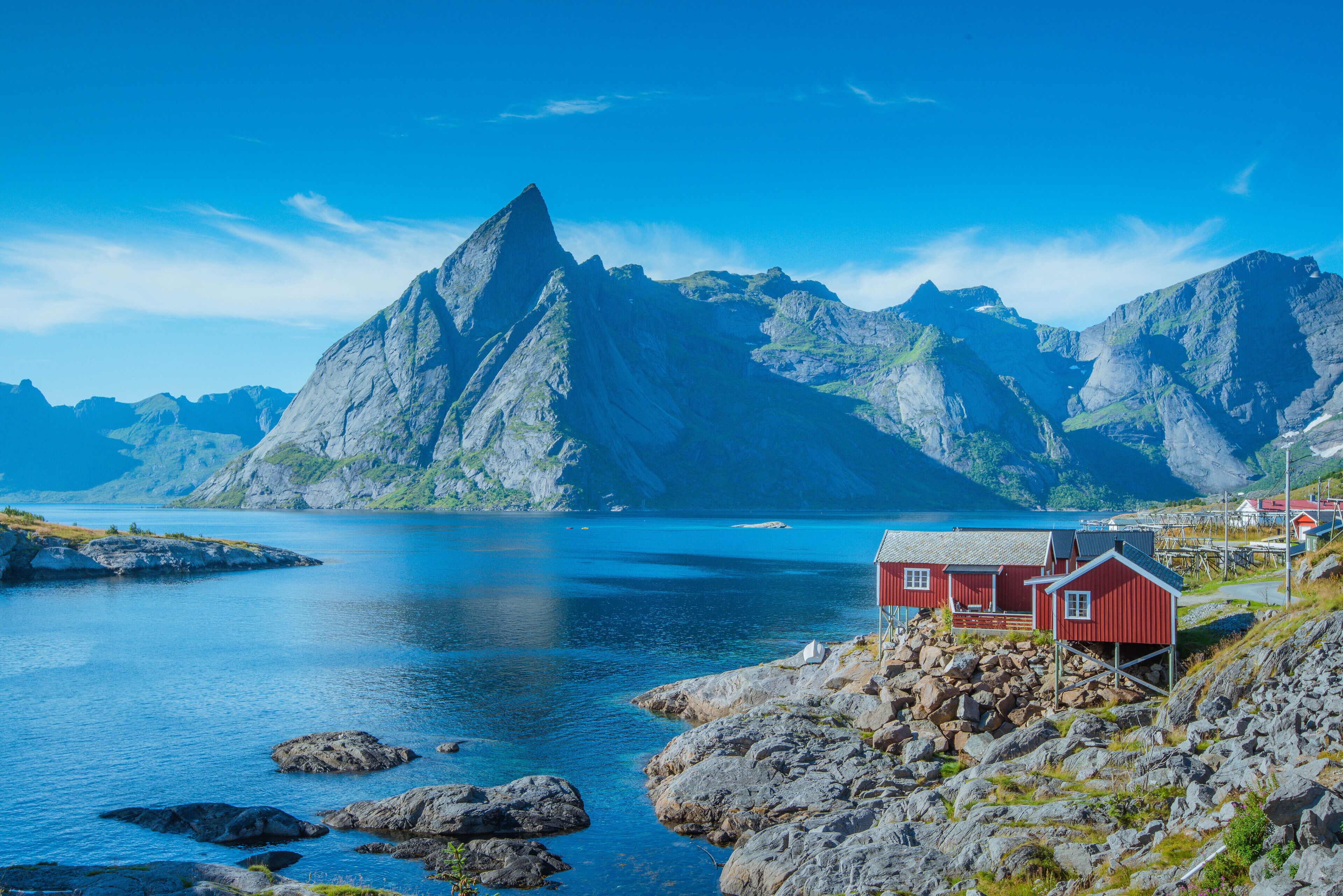 A coastal scene with a prominent mountain, a red building, and rocky terrain.