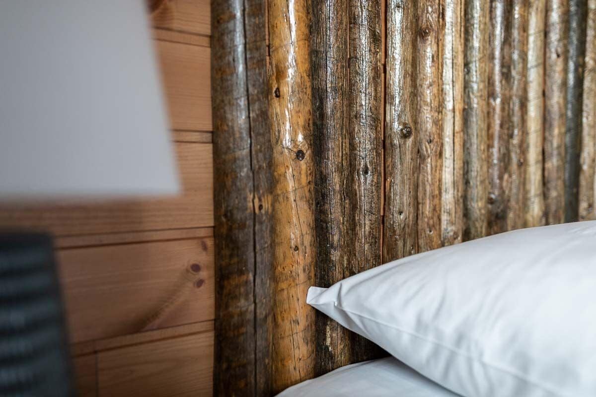 Un mur en bois avec un revêtement texturé et un coussin blanc sur un lit.