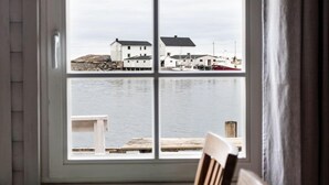 Ruokailutila, jossa on pöytä ja tuolit, ikkuna, josta avautuu näkymä satamaan, sekä kattokruunu.
