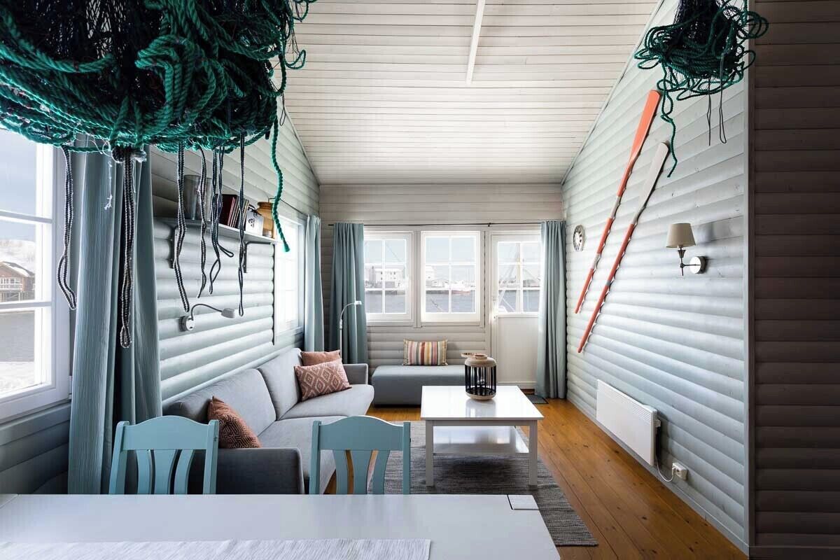 A cozy living room with a sofa, chairs, a coffee table, and a view through large windows.