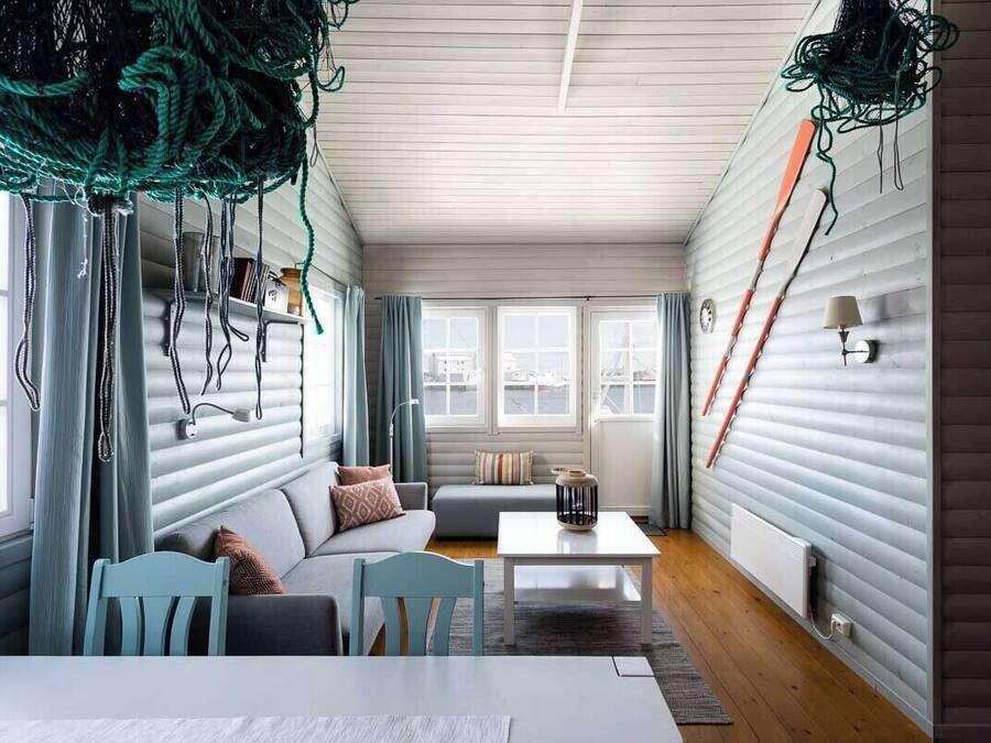 Una sala de estar acogedora con un sofá, sillas, una mesa de centro y vistas amplias a través de grandes ventanales.
