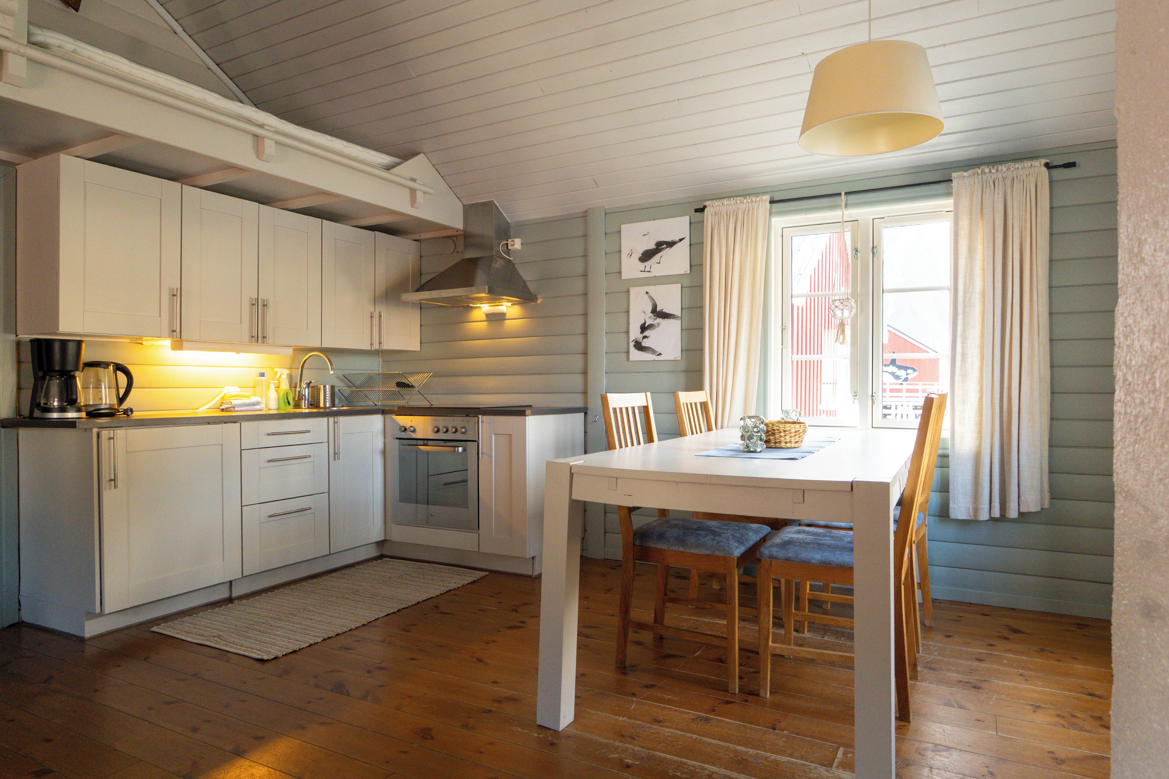 A kitchen with white cabinets, a stove, and a dining area with a table and chairs.