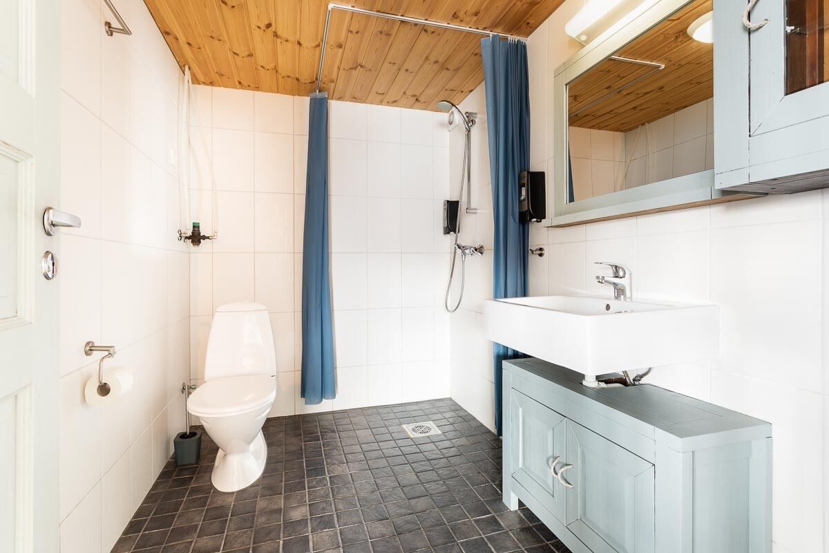 A bathroom with a white toilet, a shower with a blue curtain, a white sink, and a cabinet.