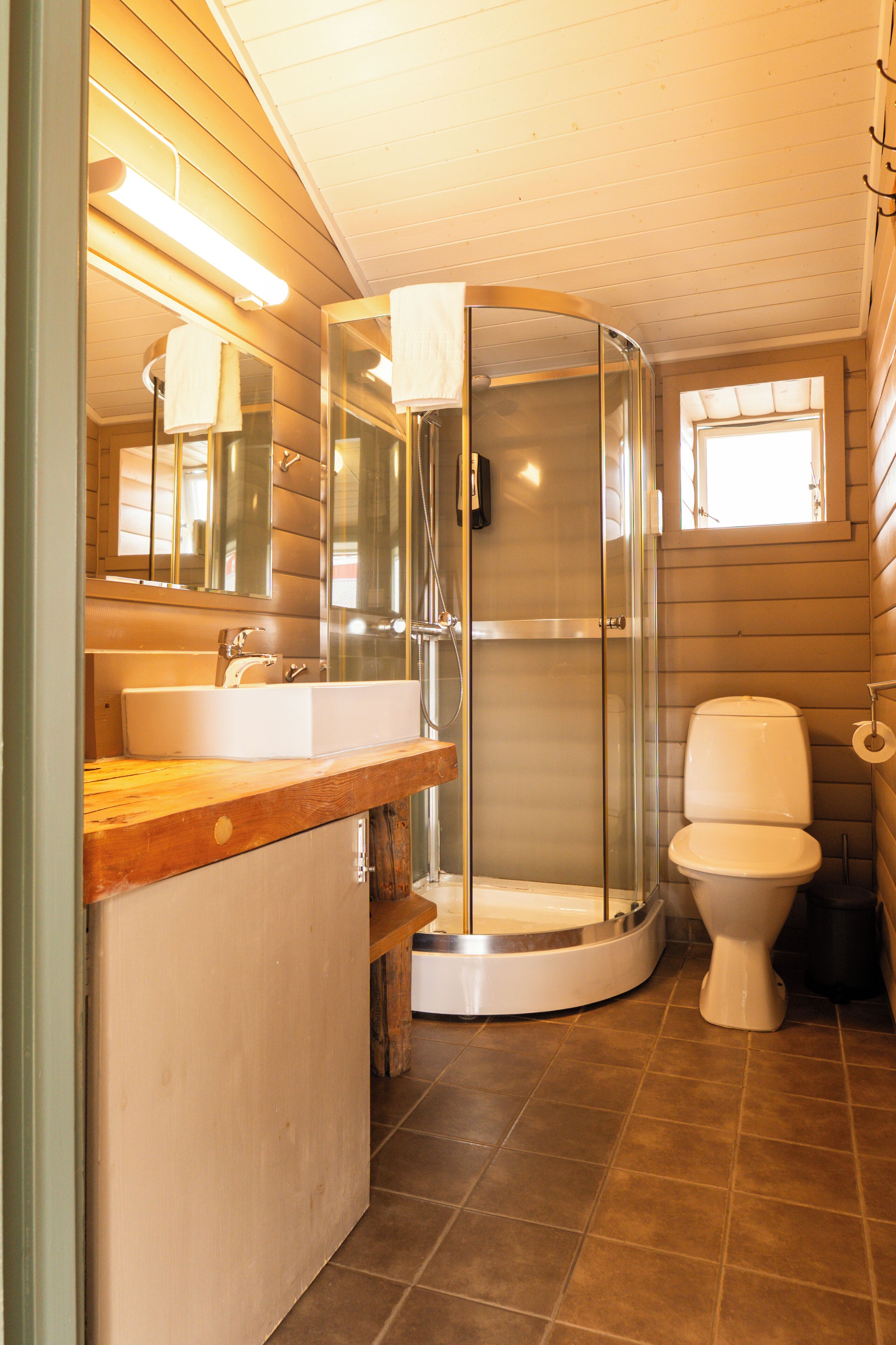 Ein Badezimmer mit einem Holz-Waschtisch, einer Duschkabine und einer Toilette.