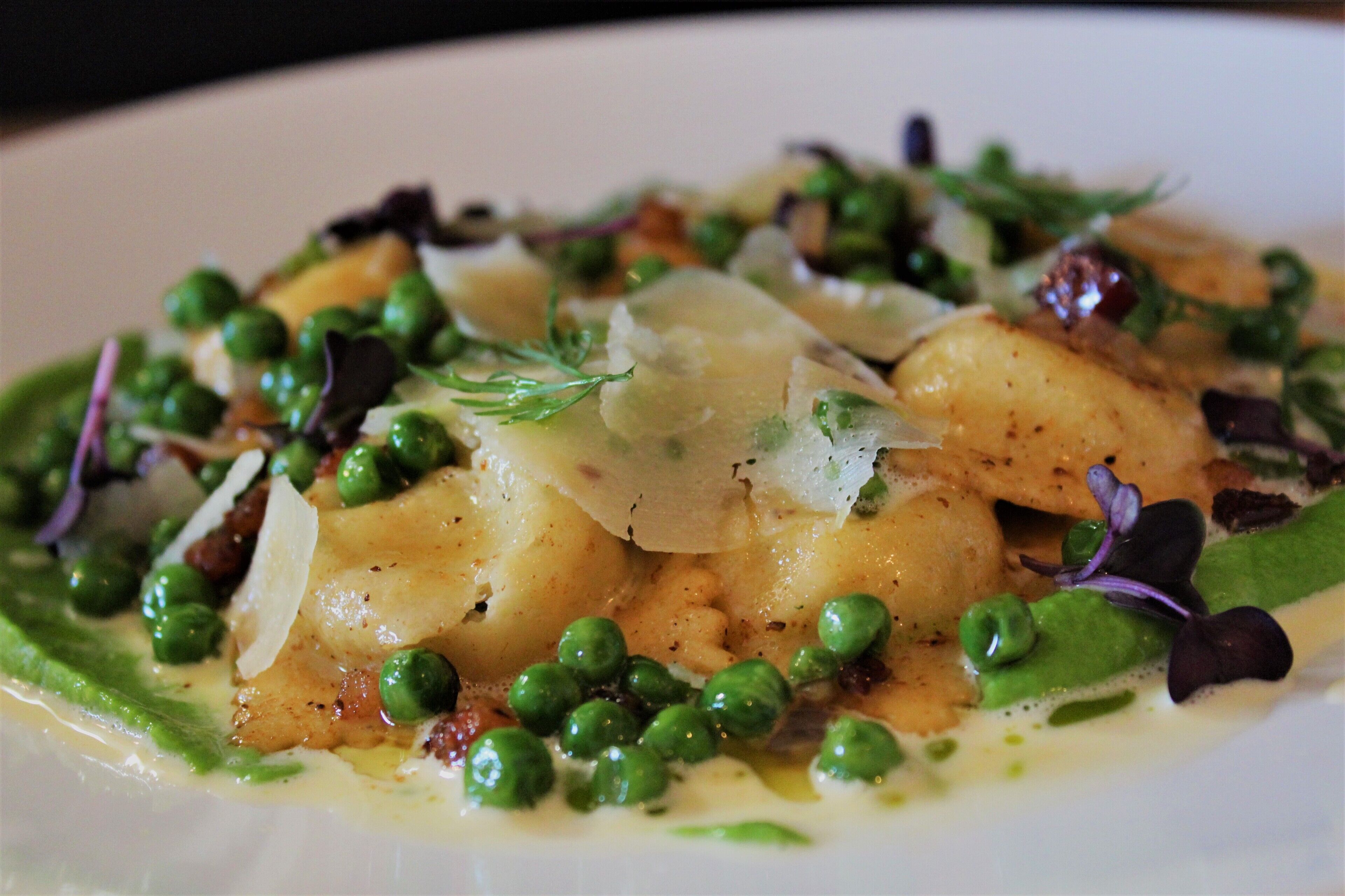 A plate of food with green peas, potatoes, and a creamy sauce.