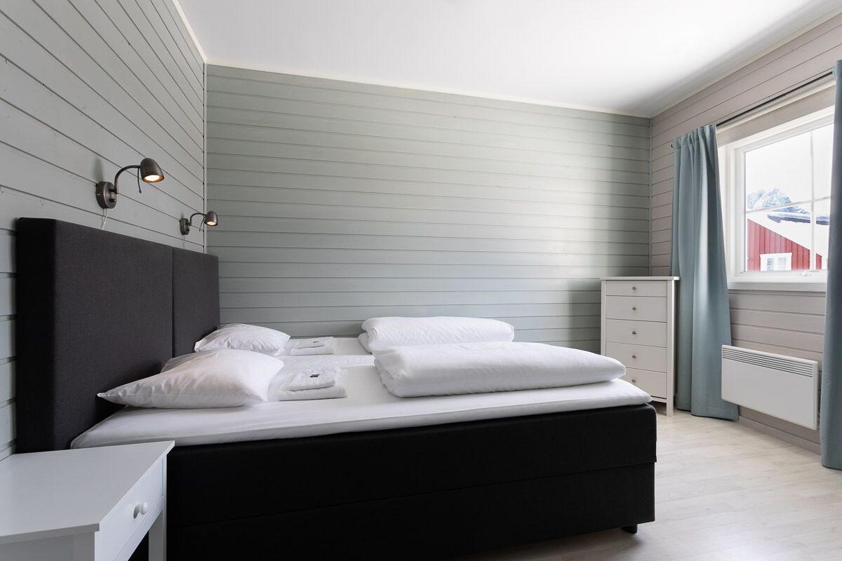 Un dormitorio moderno con cama, mesita de noche e iluminación en la pared.