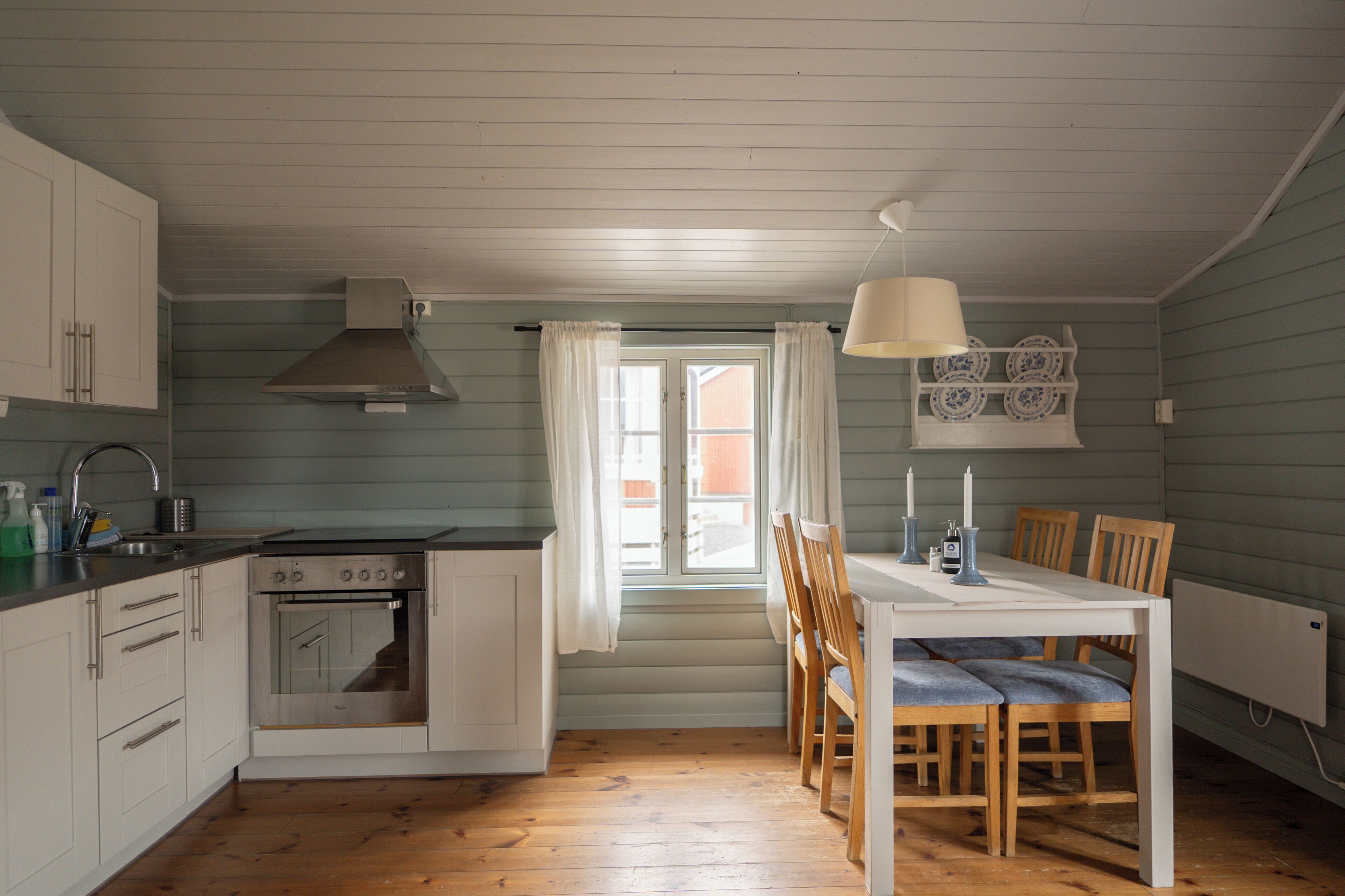 A kitchen with wooden cabinets, a stove, and a dining table with chairs.