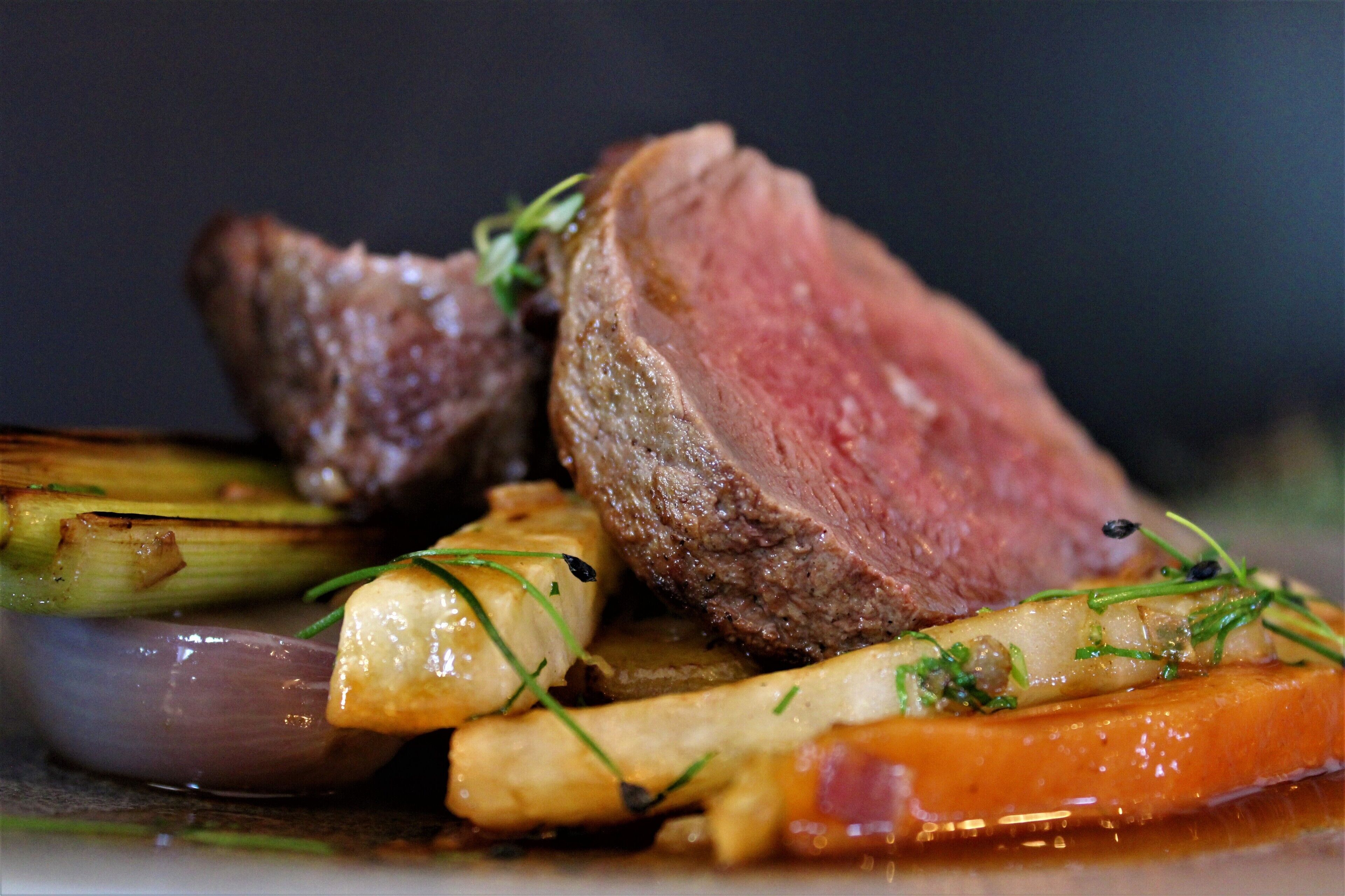 A close-up of a cooked steak with vegetables.