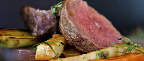 A close-up of a cooked steak with vegetables.