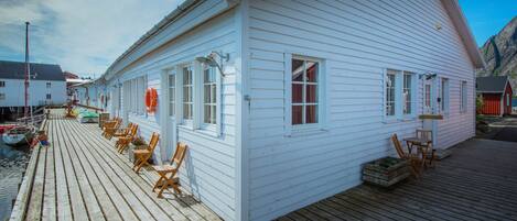 A white building with a wooden deck and outdoor seating.