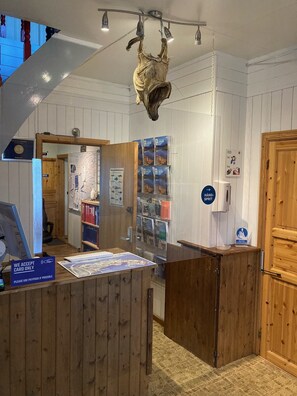 A reception desk with a wooden counter, a mounted animal skull, and various informational posters.