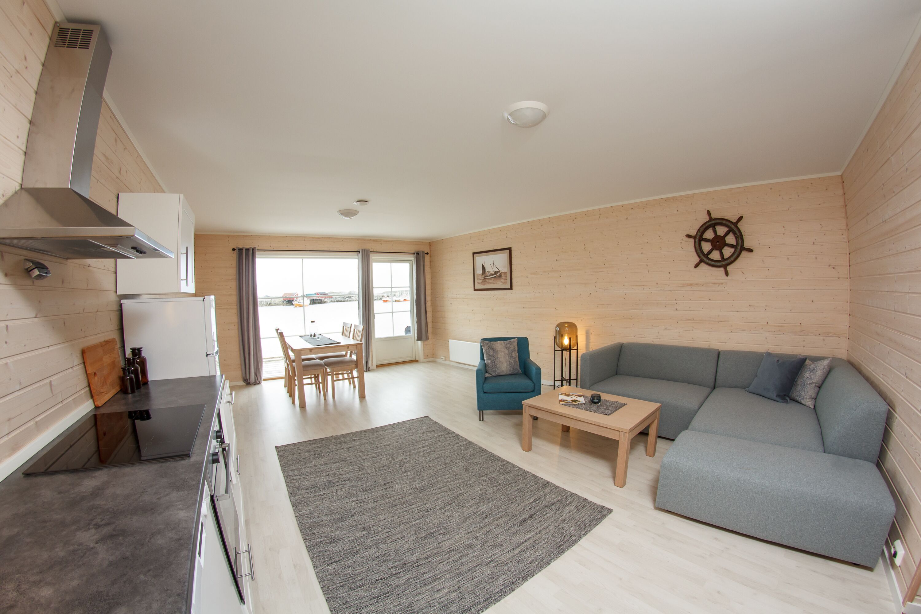 A modern living room with a grey sofa, a wooden coffee table, and a view of the city through large windows.