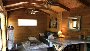 Un interior de cabaña acogedor, con techo de madera, chimenea, sofá, mesa de comedor y espejo.