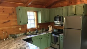 Una cocina con gabinetes verdes, un refrigerador de acero inoxidable, un microondas y una estufa.