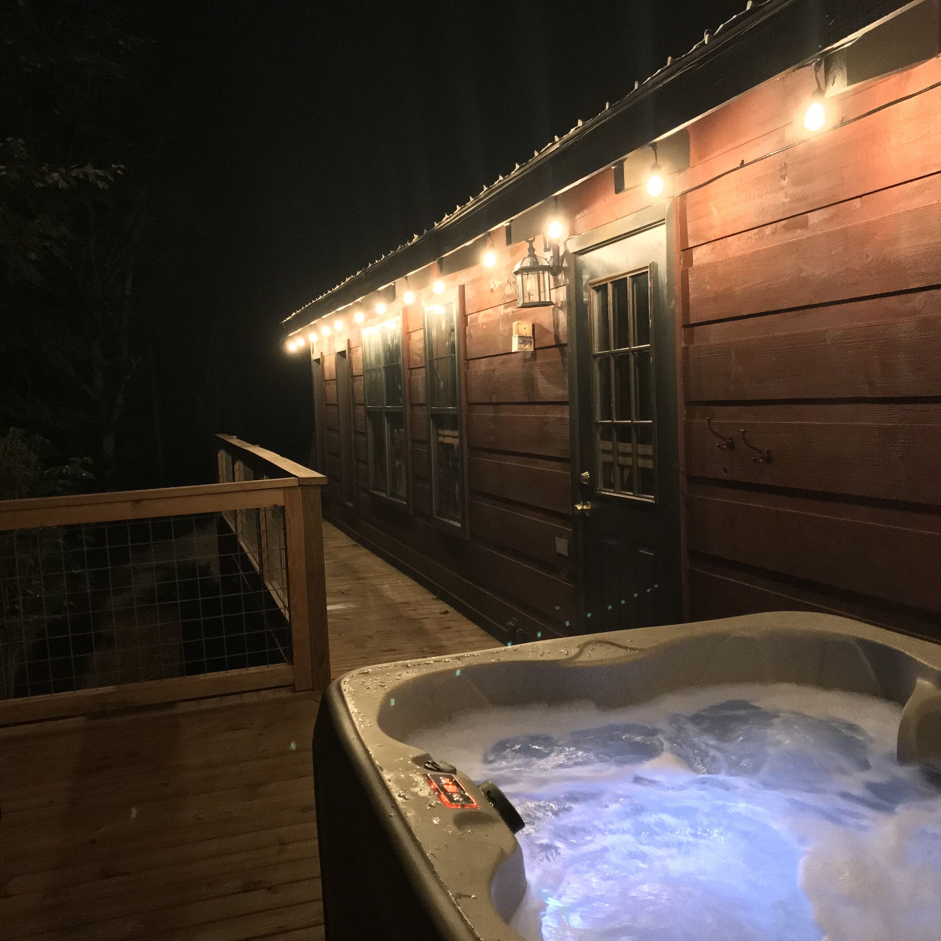 A wooden cabin with a hot tub and a deck.