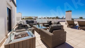 Una terrazza sul tetto con mobili in vimini, un tavolo in vetro e vista sullo skyline cittadino.