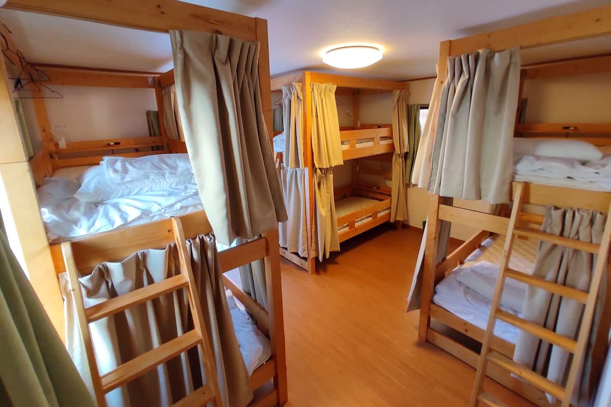 A room with bunk beds, wooden walls, and a ceiling light.