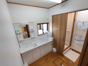 Un baño con lavamanos doble, espejo, ventana y zona de ducha.