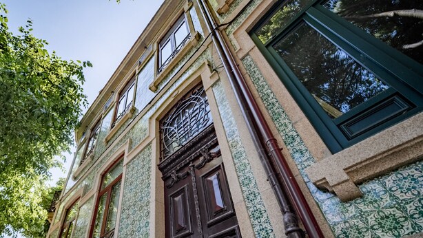 A historic building with ornate ironwork, a large wooden door, and patterned tiles. - Nomads Nest in Bonfim 1BED Balcony View (Porto)