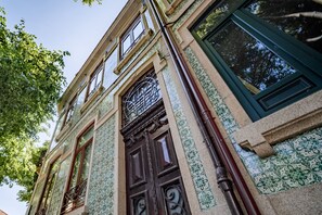 Ein historisches Gebäude mit aufwendiger Eisenverzierung, einer großen Holztür und gemusterten Fliesen.