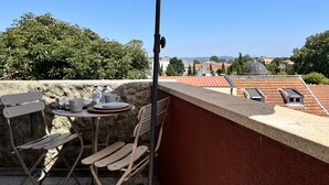 A terrace with a table and chairs, a beige umbrella, and a view of buildings and trees. - Nomads Nest in Bonfim 1BED Balcony View (Porto)