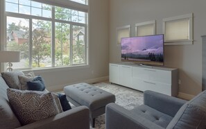 A living room with a large window, a flat-screen TV, and a white entertainment unit.