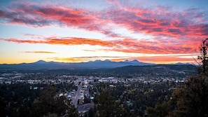 A panoramic view of a town with mountains in the background and a colorful sunset sky.