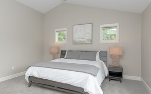 A bedroom with a bed, two bedside lamps, a window, and a painting on the wall. - Private Hot Tub ~ Dog Friendly ~ Trail access to Pilot Butte ~ Fireplace (Bend)