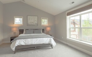 A bedroom with a bed, two bedside lamps, a window with blinds, and a wall-mounted artwork. - Private Hot Tub ~ Dog Friendly ~ Trail access to Pilot Butte ~ Fireplace (Bend)