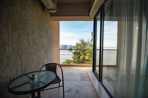 Uma varanda com porta de vidro, uma mesa pequena e uma cadeira.