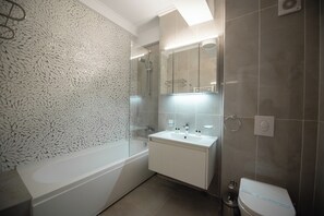 A modern bathroom with a freestanding bathtub, a vanity with a mirror, and a toilet. - Solid Magic Apart-Hotel (Constanta)