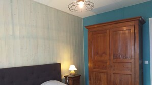 Un dormitorio con cama, armario de madera, mesita de noche con lámpara y lámpara en el techo.