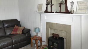 Een woonkamer met een open haard, een bank, een lamp en een spiegel.