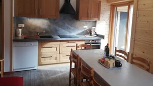 Una cocina moderna con armarios de madera, extractor de acero inoxidable y comedor con mesa dispuesta para cuatro.