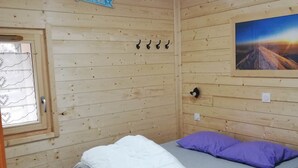Una habitación de cabaña de madera con cama, ventana, un letrero en la pared y un cuadro.