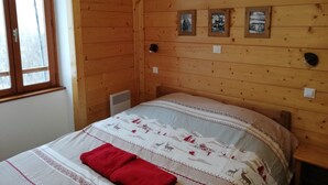 A wooden-paneled room with a bed, a window, and three framed pictures on the wall.