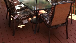Une terrasse extérieure avec une table en verre, des chaises à motifs et un parasol rayé.