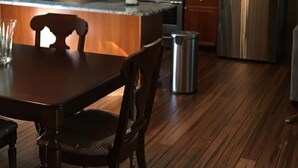 Une cuisine avec des meubles en bois, un réfrigérateur en acier inoxydable, un four encastré et une table à manger avec des chaises.