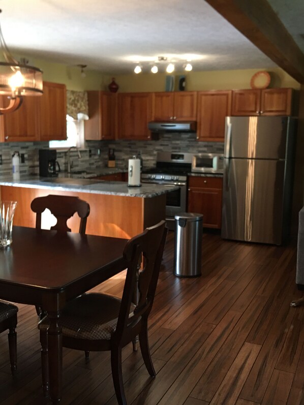 A kitchen with wooden cabinets, a stainless steel refrigerator, a built-in oven, and a dining table with chairs.
