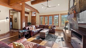 A spacious living room with a large sectional sofa, a glass coffee table, and a fireplace. - Central to All Ski Areas, Private Hot Tub; Spacious Open Concept (Breckenridge)