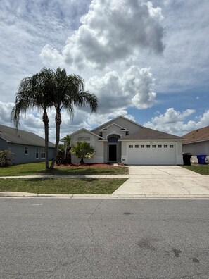 A residential house with a garage, a driveway, and a well-maintained lawn.