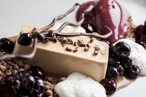 A dessert with chocolate sauce, nuts, and berries.
